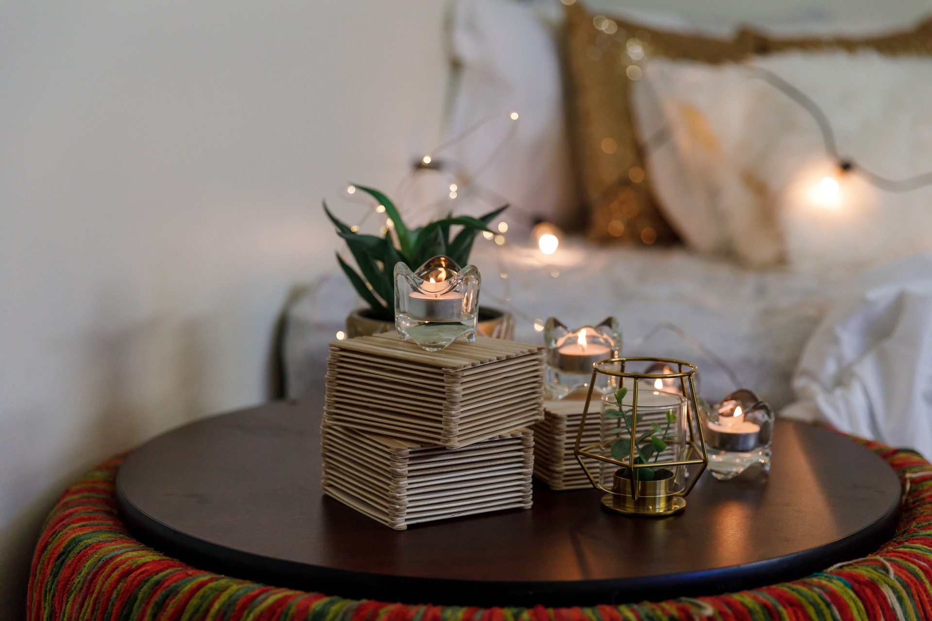 A cozy bedside table with candles and lamps.