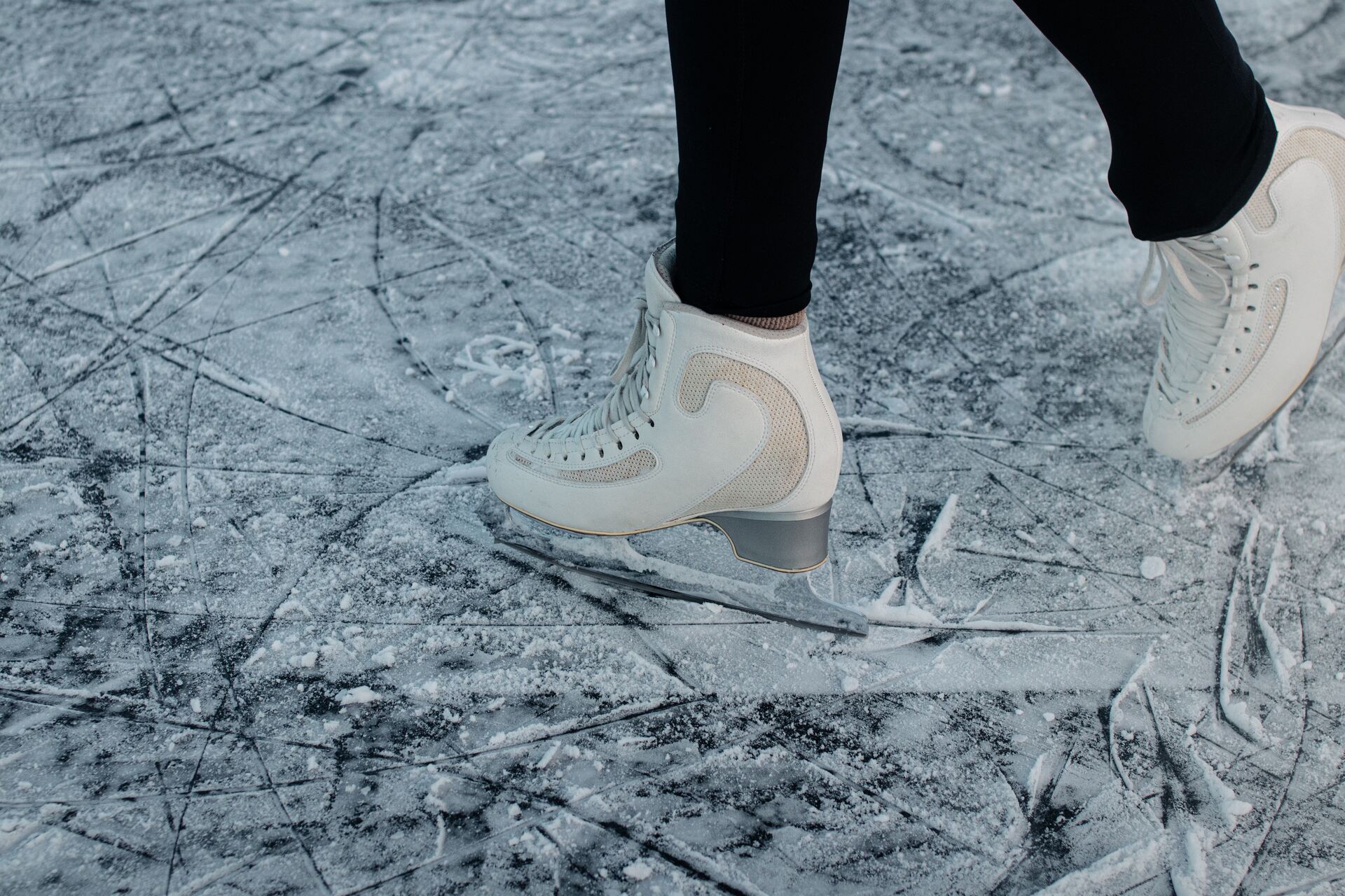 Person in white ice skates walking on frozen surface.